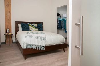 A bedroom with a bed, a nightstand, and a closet.